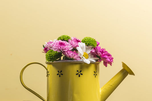 a watering can with flowers in it on a table